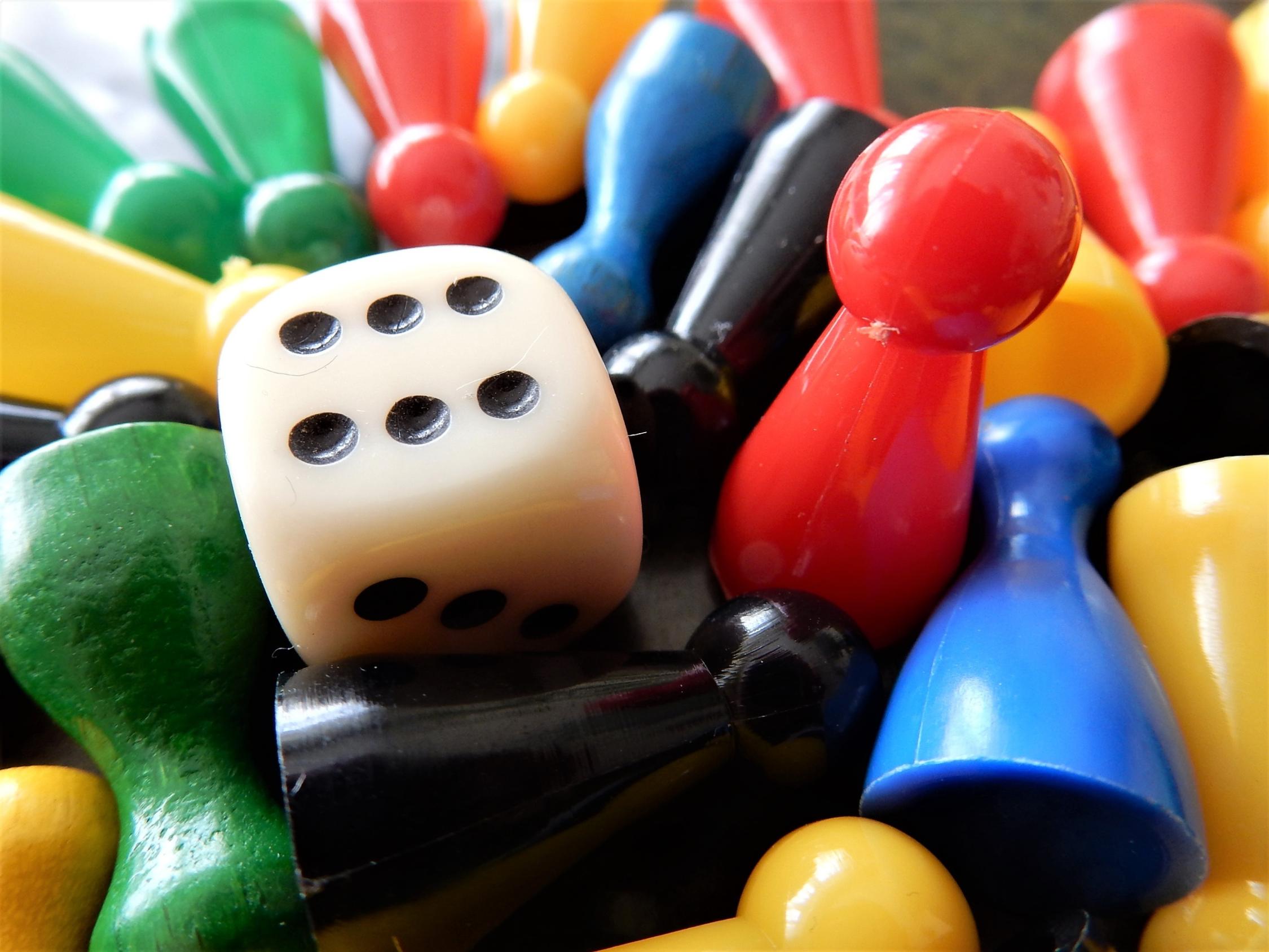 Bunte Spielfiguren mit einem weißen Würfel in der Mitte.