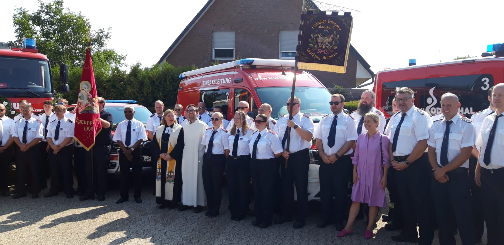 Gruppenbild mit Feuerwehrleuten, Kirchenvertretern und Bürgermeisterin vor den Fahrzeugen der Einheit Scheuren der Freiwilligen Feuerwehr Odenthal